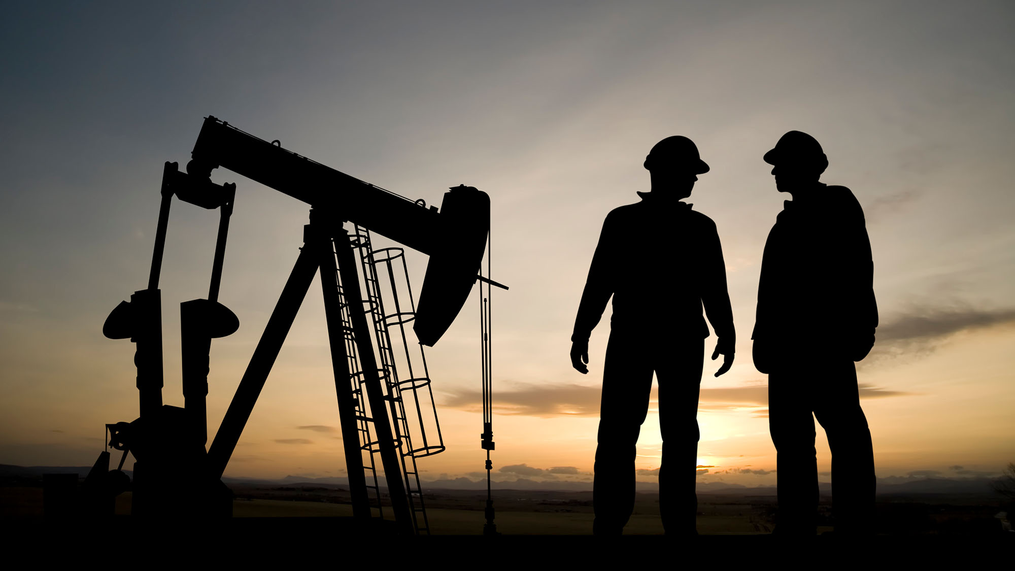 workers in silhouette at drill site