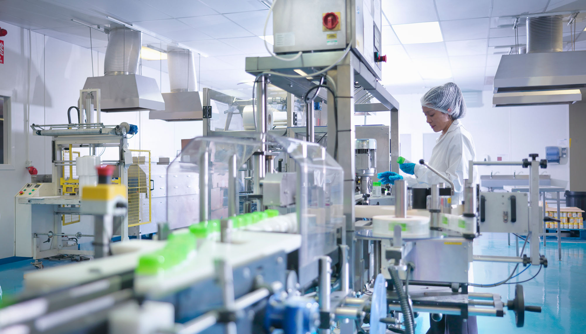 Worker inspecting products on production line in pharmaceutical factory